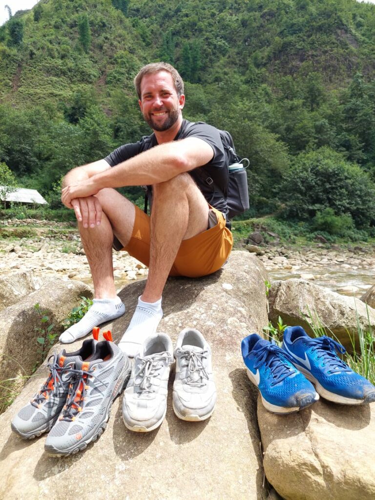 Davis sitting on a rock with 3 pairs of shoes