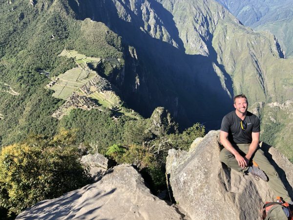 Davis on a cliff overlooking a green valley